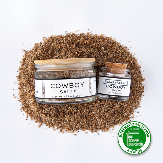 Top-down image of Texas Salt Co.’s Cowboy Salt in 3.75 oz and 0.5 oz jars on a bed of smoked salt, featuring a green Flave Award badge.