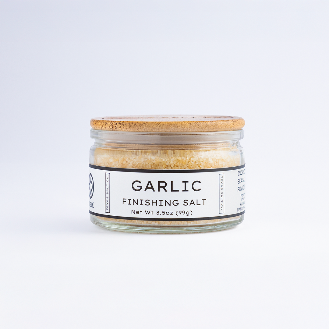 3.5 oz jar of Texas Salt Co. Garlic Finishing Salt with bamboo lid, shown on a white background.