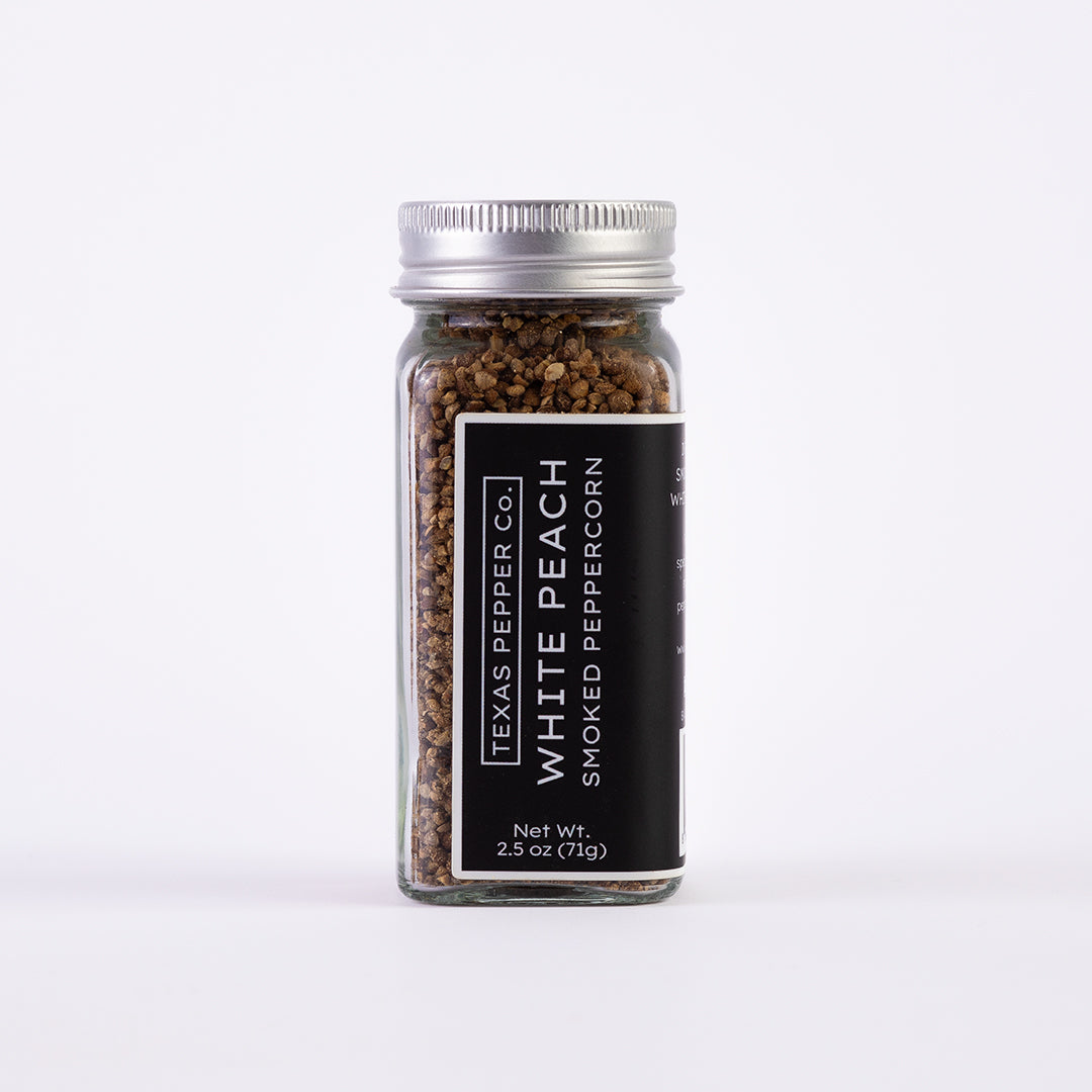 Glass jar of Texas Pepper Co. White Peach Smoked Peppercorn, 2.5 oz (71g), with silver lid and black label.