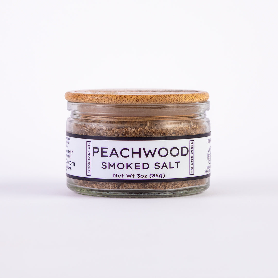 Glass jar of Texas Salt Co. Peachwood Smoked Salt, 3 oz (85g), with bamboo lid and white label.