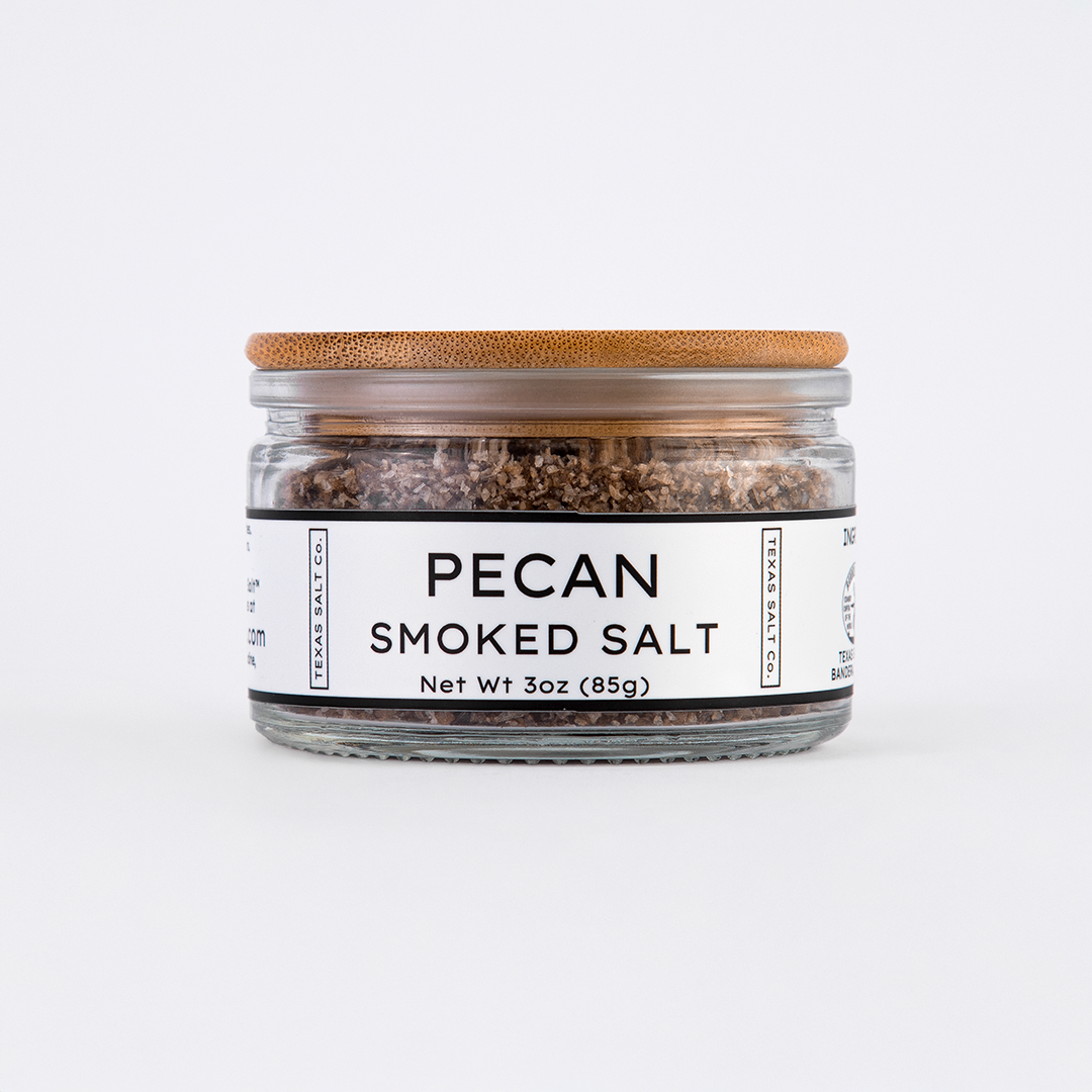 Glass jar of Texas Salt Co. Pecan Smoked Salt, 3 oz (85g), with bamboo lid and white label, filled with coarse smoked salt.