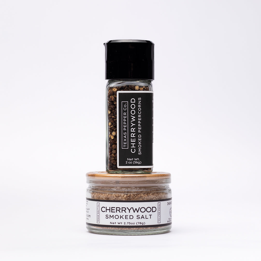 Cherrywood Smoked Peppercorn with grinder top and a bamboo-lid salt jar stacked beneath it, both featuring Texas Salt Co. labels