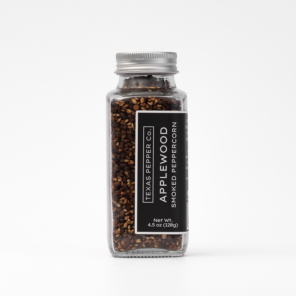 Glass jar of Applewood smoked peppercorn with Texas Pepper Co. label on a white background