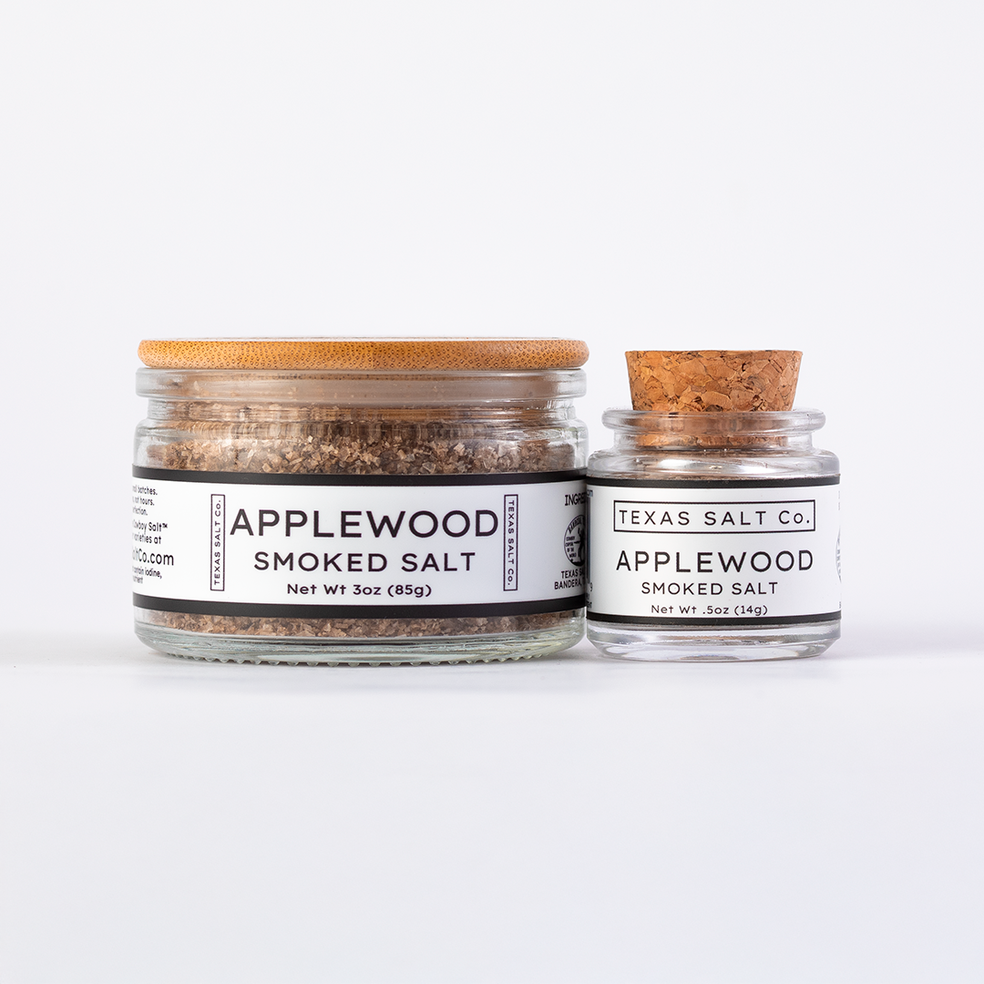 Texas Salt Co. Applewood Smoked Salt in 3oz bamboo-lid jar and .5oz cork-top jar displayed side by side on a white background.