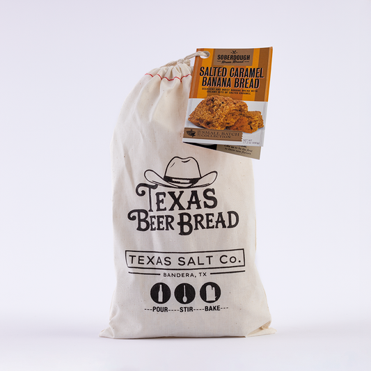 Texas Salt Co. Texas Beer Bread mix in a cloth bag with a Salted Caramel Banana Bread flavor tag attached, labeled with “Pour, Stir, Bake” instructions.