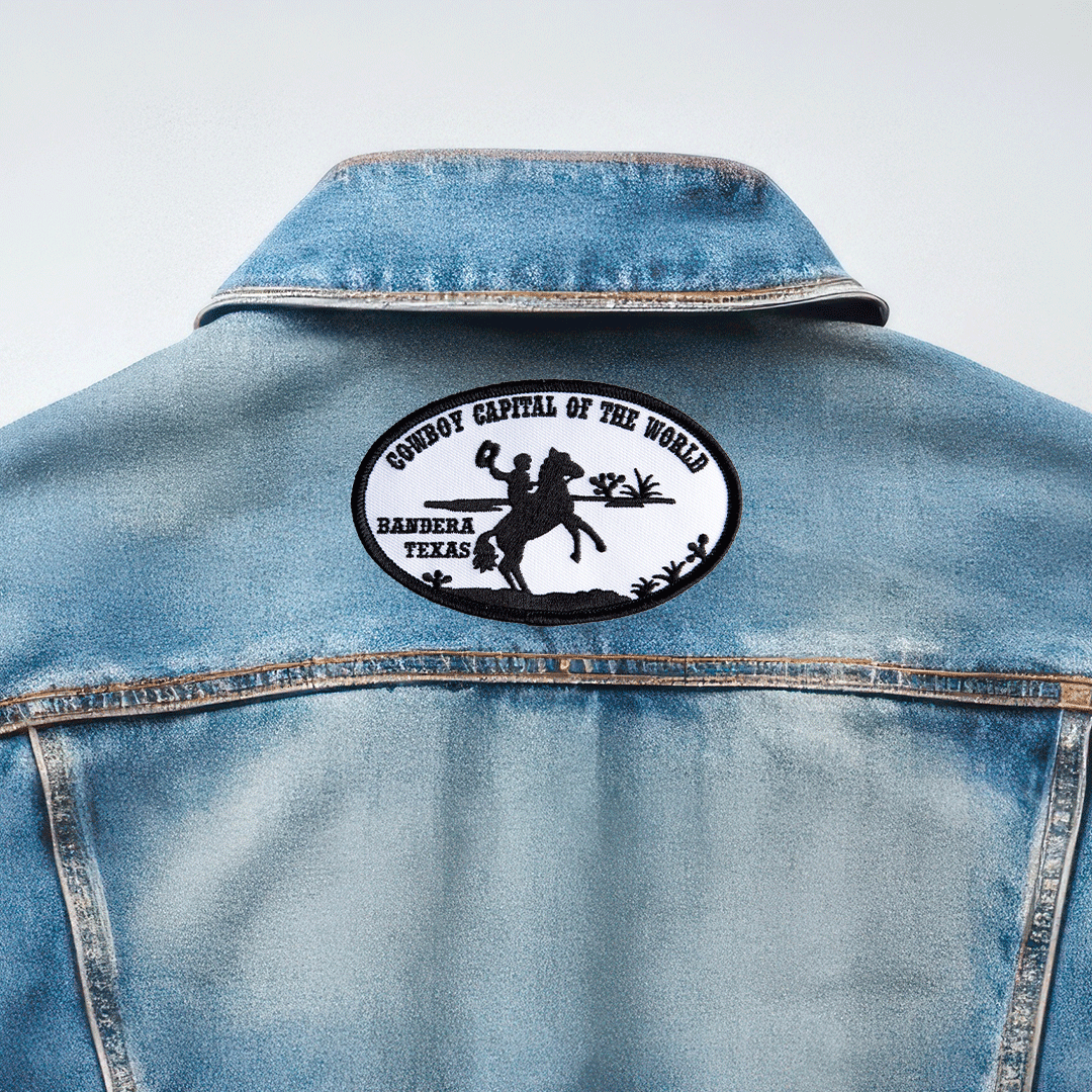 Back of denim jacket featuring black and white embroidered patch reading "Cowboy Capital of the World, Bandera Texas" with cowboy silhouette