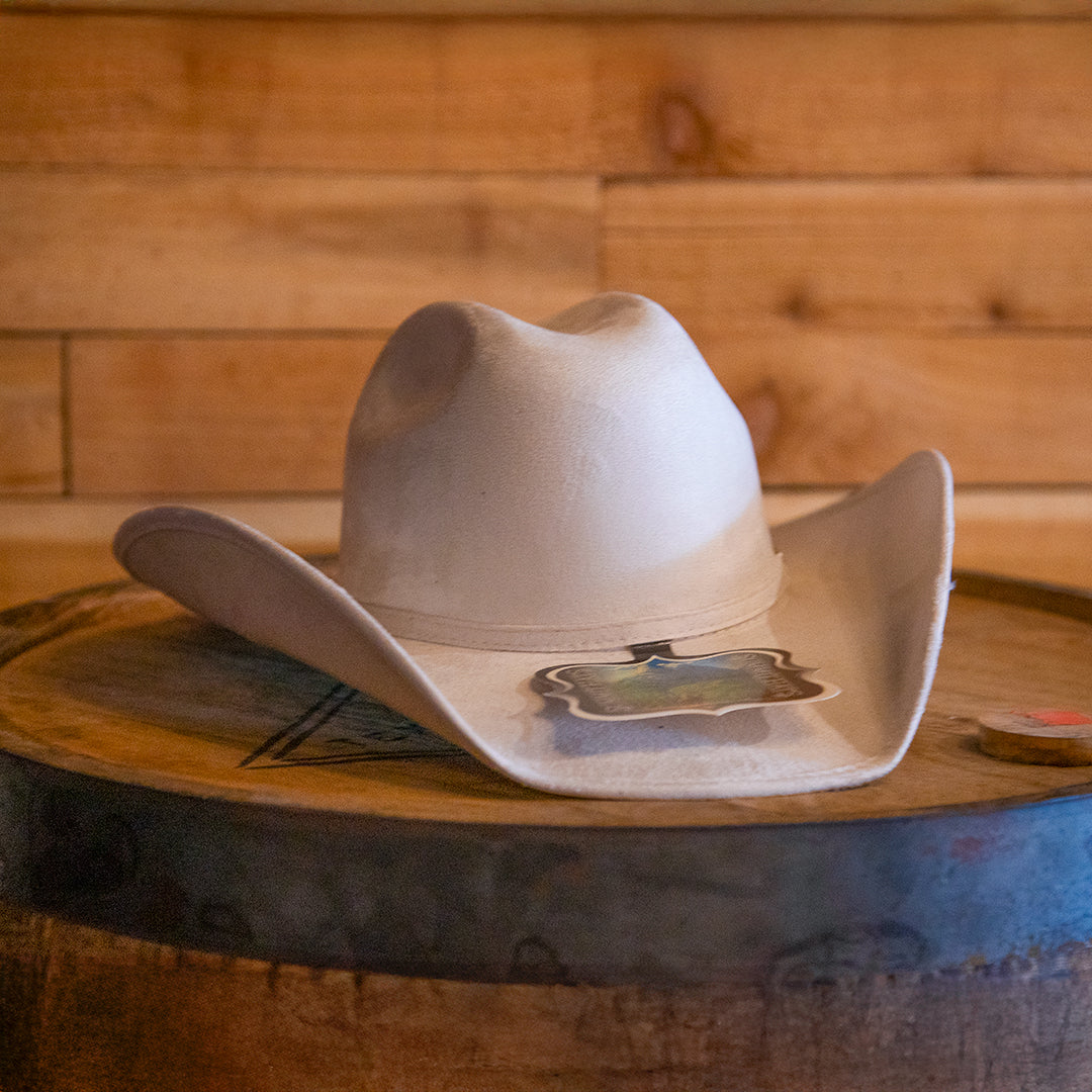 Beige cowboy hat on a wooden barrel with a wooden wall background