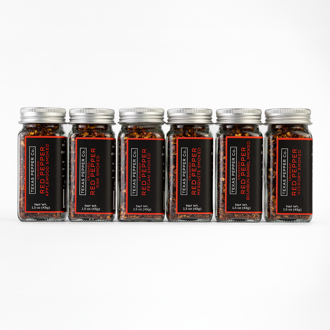 Six jars set of Texas Pepper Co. Red Pepper featuring Applewood, Oak, Pecan, Mesquite, Bourbon Barrel, and Hickory on a white background.