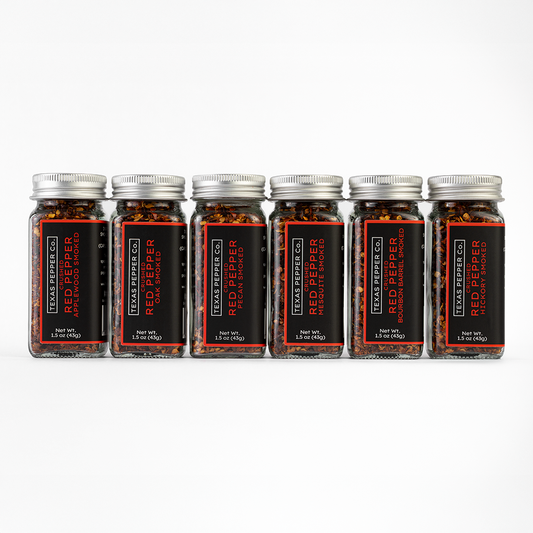 Six jars set of Texas Pepper Co. Red Pepper featuring Applewood, Oak, Pecan, Mesquite, Bourbon Barrel, and Hickory on a white background.