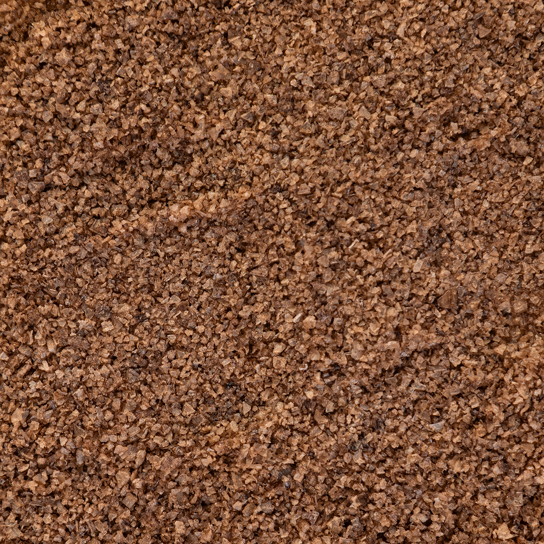 Close-up texture shot of Texas Salt Co. Hickory Smoked Salt showing coarse grains and natural hickory-smoke color.