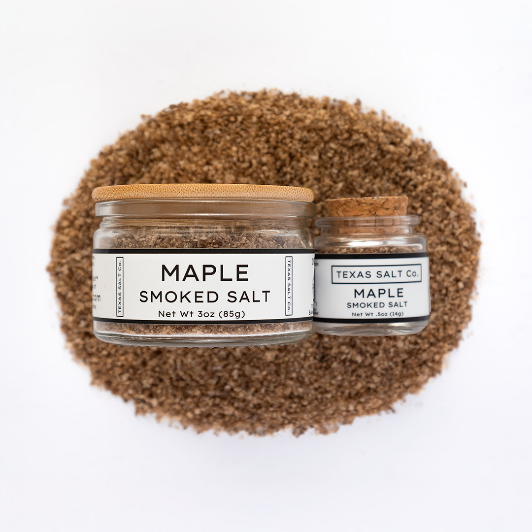 Texas Salt Co. Maple Smoked Salt 3oz and .5oz jars displayed on top of a circular pile of maple-smoked salt in a top-down composition.