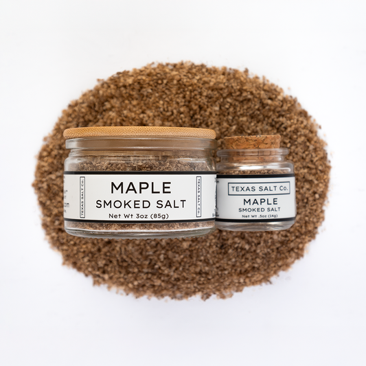 Texas Salt Co. Maple Smoked Salt 3oz and .5oz jars displayed on top of a circular pile of maple-smoked salt in a top-down composition.