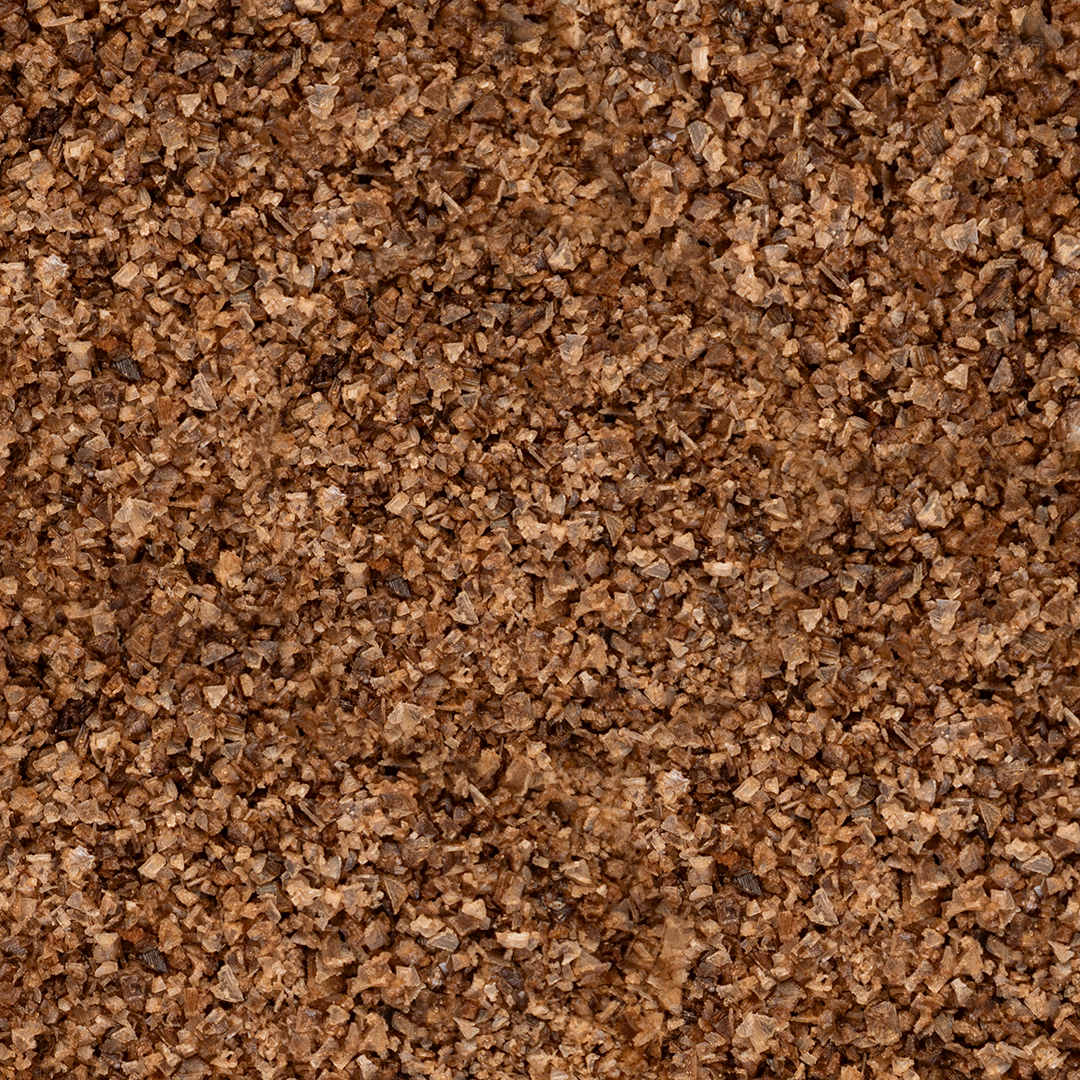 Close-up texture shot of Texas Salt Co. Mesquite Smoked Salt showing coarse grains and natural mesquite-smoke color.