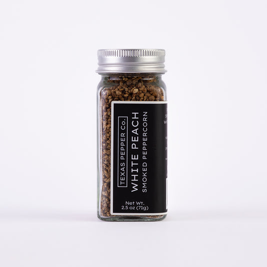 Glass jar of Texas Pepper Co. White Peach Smoked Peppercorn, 2.5 oz (71g), with silver lid and black label.