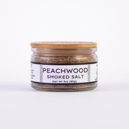 Glass jar of Texas Salt Co. Peachwood Smoked Salt, 3 oz (85g), with bamboo lid and white label.