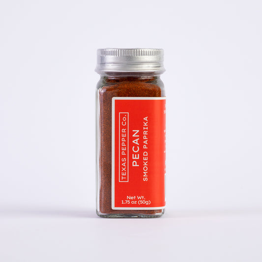 1.75oz glass jar of Texas Pepper Co. Pecan Smoked Paprika on a white background