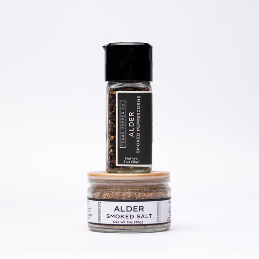 Set of two jars including a grinder-top Alder Smoked Peppercorn and a flat bamboo-lid Alder Smoked Salt, both with white Texas Salt Co. labels