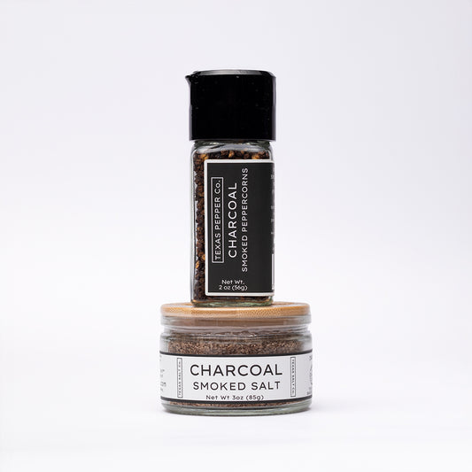 Charcoal Smoked Peppercorn in a grinder jar stacked with matching bamboo-lid Charcoal Smoked Salt jar, both with black and white labels