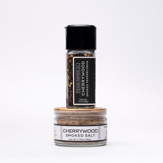 Cherrywood Smoked Peppercorn with grinder top and a bamboo-lid salt jar stacked beneath it, both featuring Texas Salt Co. labels