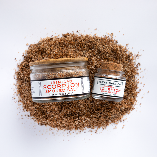 Texas Salt Co. Trinidad Scorpion Smoked Salt – Overhead view of 3.5 oz and .5 oz glass jars on a bed of ultra-spicy smoked salt