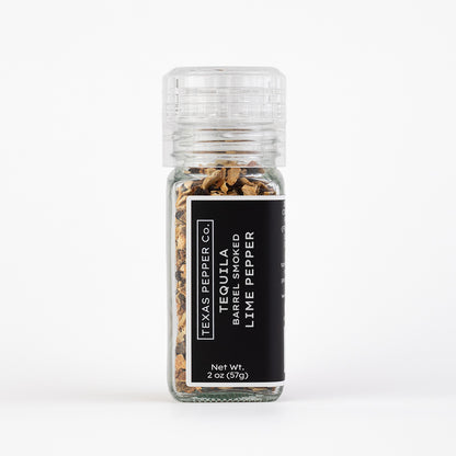 Glass jar of lime pepper with a black label on a white background